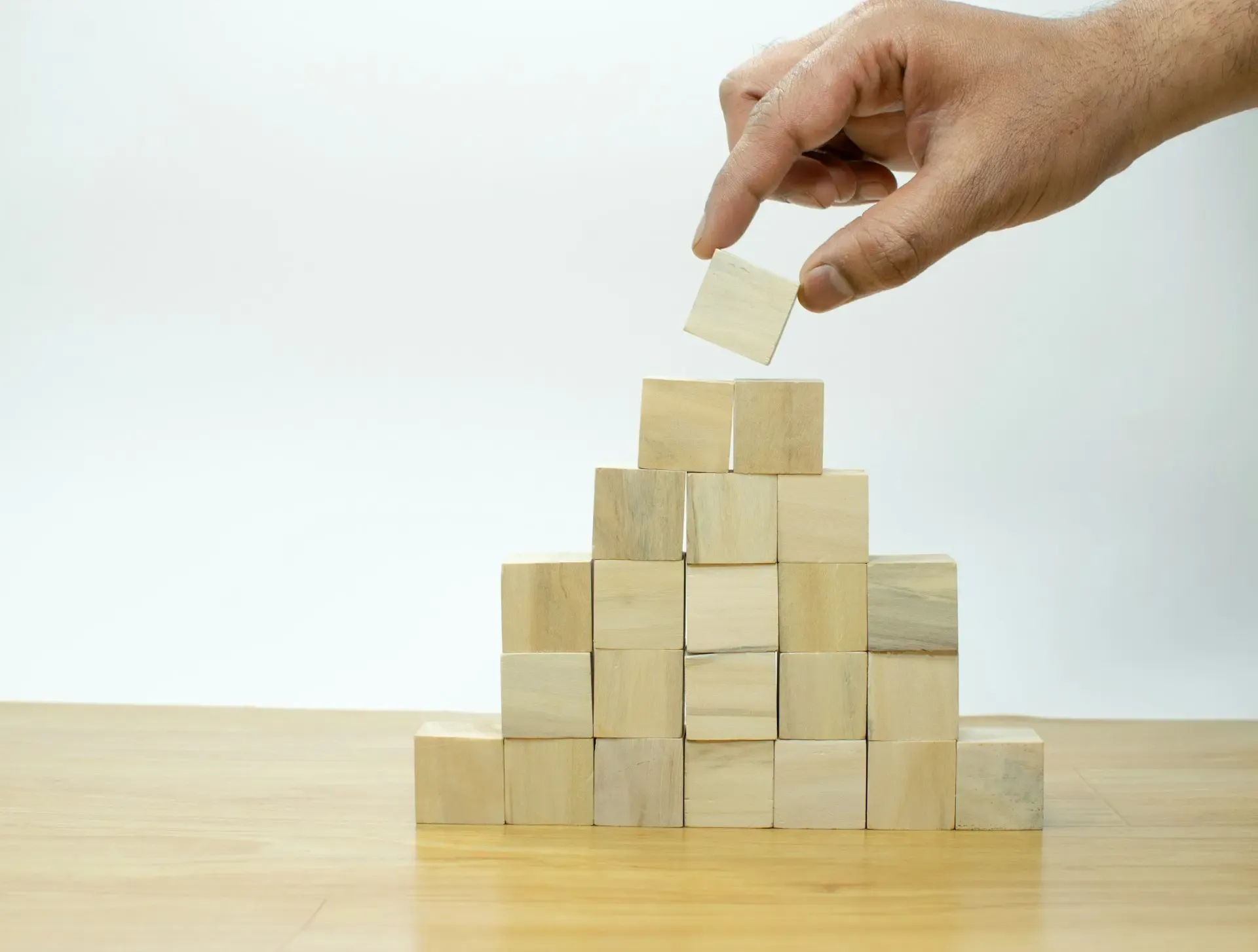 Ruka slaže drvene kockice u obliku piramide, simbol strateškog planiranja